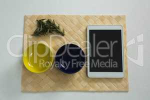 Rosemary and empty bowls with digital tablet on place mat