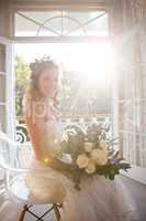 Portrait of happy bride holding bouquet while sitting on chair
