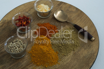 Various spices on wooden board with spoon