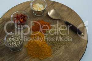 Various spices on wooden board with spoon