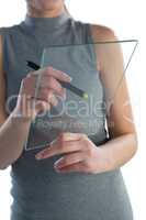 Mid section of businesswoman writing on glass interface