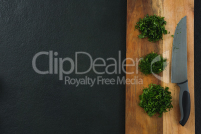 Chopped herbs with knife on chopping board