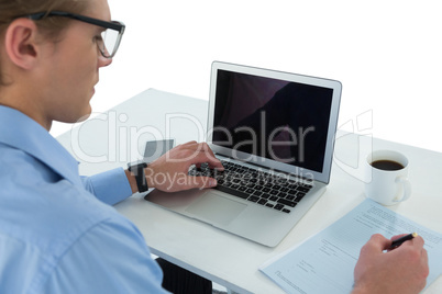 High angle view of businessman using laptop while writing on document