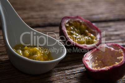 Two passion fruit and spoon with passion fruit pulp on wooden table
