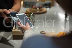 Woman paying bill through smartphone using NFC technology