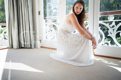 Beautiful bride looking away while crouching by door