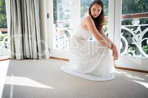 Beautiful bride looking away while crouching by door