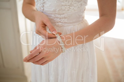 Midsection of bride wearing bracelet at home