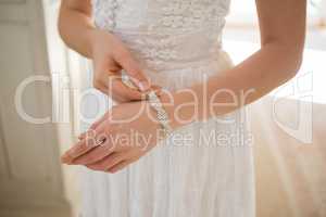 Midsection of bride wearing bracelet at home