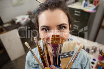 Woman holding various brushes in drawing class