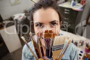 Woman holding various brushes in drawing class
