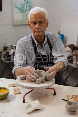 Portrait of senior man molding clay