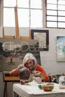 Attentive senior woman making a clay sculpture