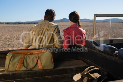 Rear view of couple by off road vehicle looking at landscape