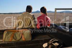 Rear view of couple by off road vehicle looking at landscape