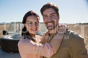 Portrait of smiling couple by off road vehicle