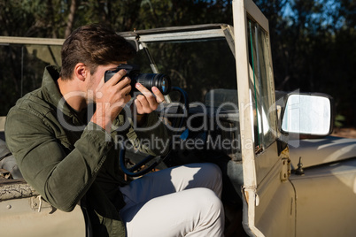 Man photographing while sitting in vehicle