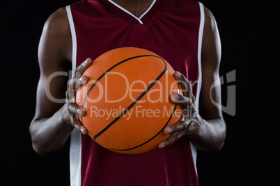 Mid section of player holding basketball