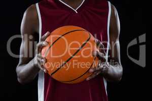 Mid section of player holding basketball