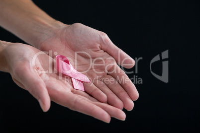 Cropped image of hands holding pink ribbon