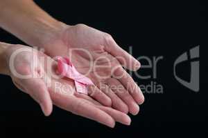 Cropped image of hands holding pink ribbon
