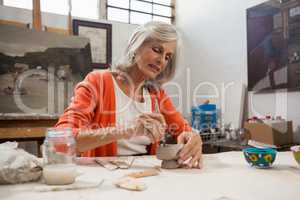 Attentive senior woman shaping a clay pot