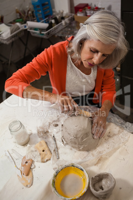 Attentive senior woman shaping a molded clay