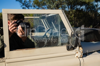 Man photographing while sitting in off road vehicle