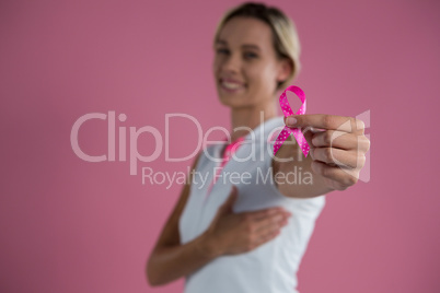 Portrait of smiling female with hand on breast showing Breast Cancer Awareness ribbon