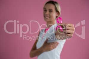 Portrait of smiling female with hand on breast showing Breast Cancer Awareness ribbon