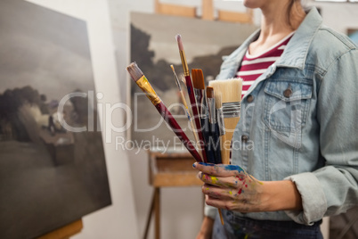 Woman holding various brushes in drawing class