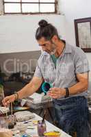 Attentive man painting bowl