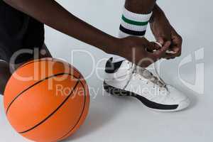 Basketball player tying shoelace on white background
