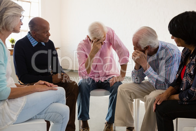 Senior friends looking at man with head in hand