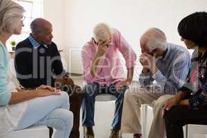 Senior friends looking at man with head in hand