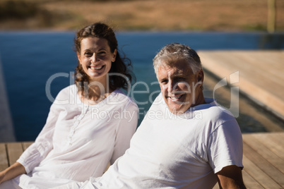 Portrait of happy couple relaxing on wooden plank