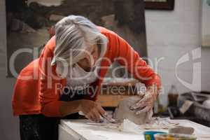 Attentive senior woman shaping a molded clay