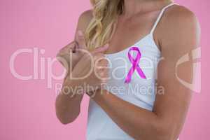 Mid section of young woman with Breast Cancer Awareness ribbon clenching fist while