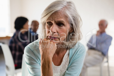 Tensed senior female with friends in background