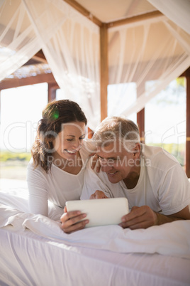 Happy couple using digital tablet on bed