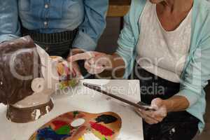 Woman using digital tablet while painting a sculptor