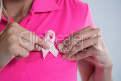 Mid section of woman attaching pink ribbon