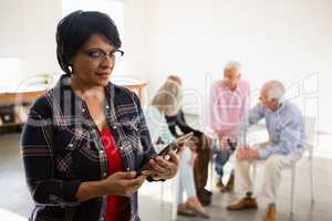 Senior woman using digital tablet with friends in background