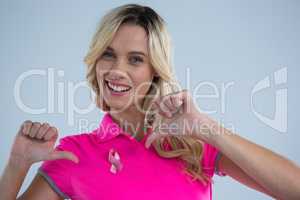 Portrait of happy woman pointing on pink ribbon