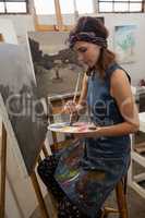 Woman painting on canvas in drawing class