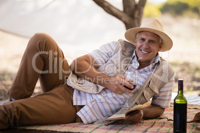 Portrait of happy man having wine while reading book in cottage
