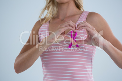 Pink ribbon seen through heart shape made by female