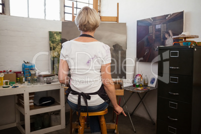 Woman painting on canvas in drawing class