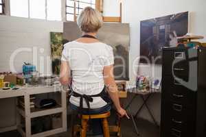 Woman painting on canvas in drawing class