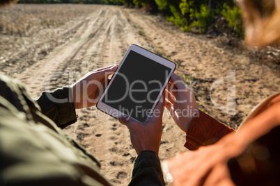 Cropped hands of couple using tablet on field